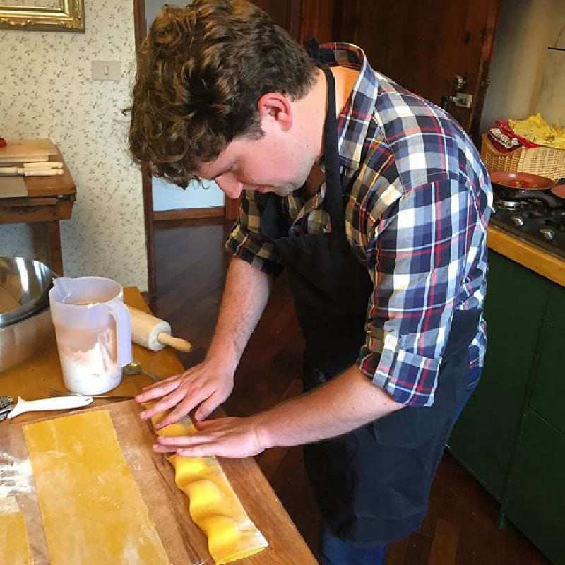 Making homemade pasta with wooden rolling pin in rustic kitchen