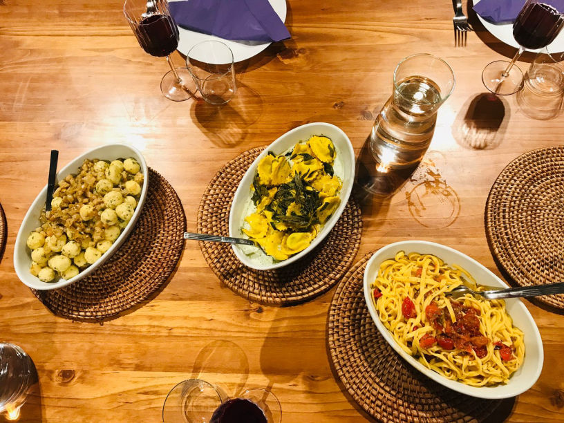 Italian dinner spread with pasta dishes and wine on wooden table